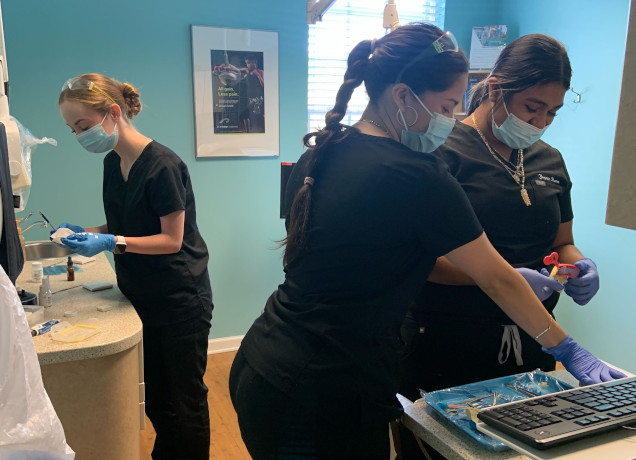 {{ school.name }} students working with dental tools in class