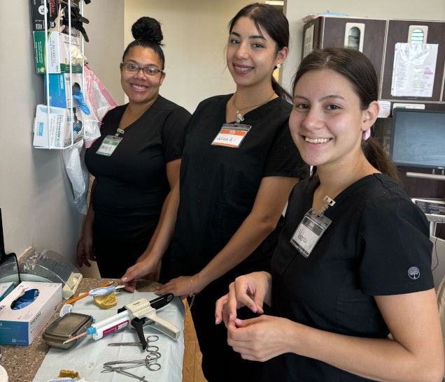 {{ school.name }} students working with dental assisting equipment in class