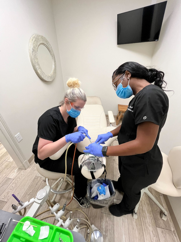 {{ school.name }} student working with their instructor on dental procedures