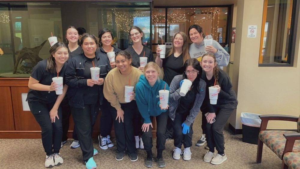 {{ school.name }} students posing with drink cups in group photo