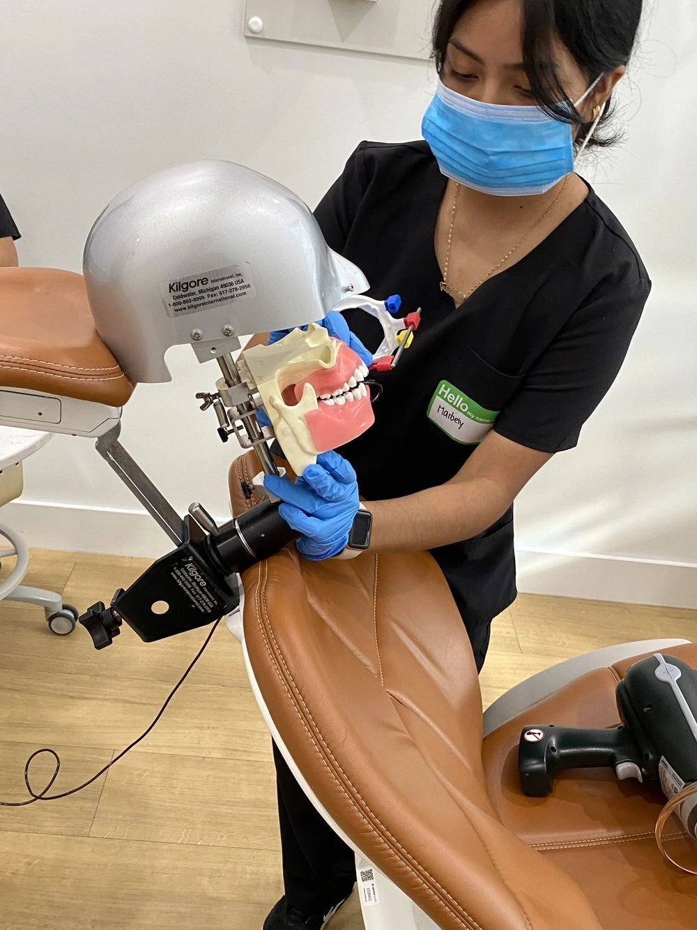 {{ school.name }} student training with dental assistant training equipment in class