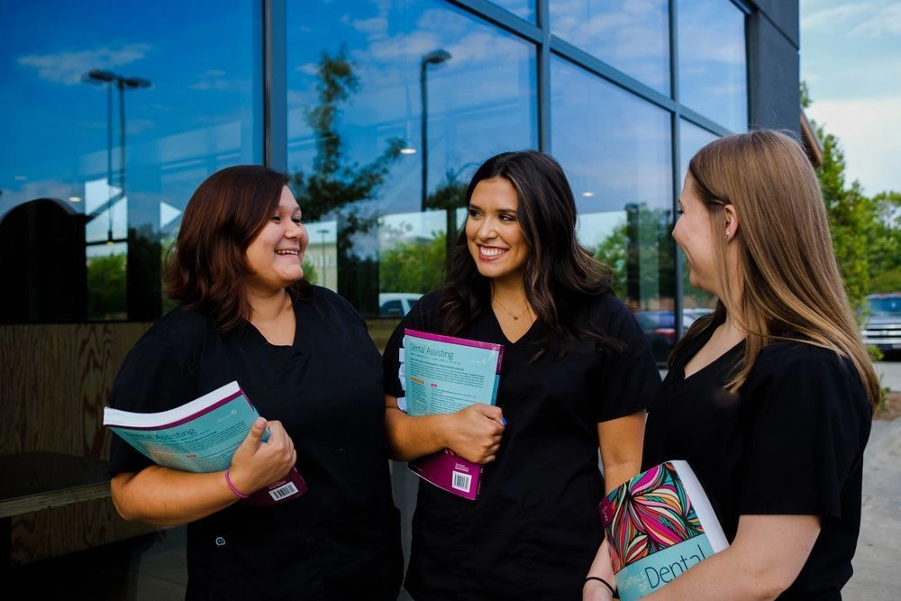 {{ school.name }} students outside of facility with their workbooks in hand